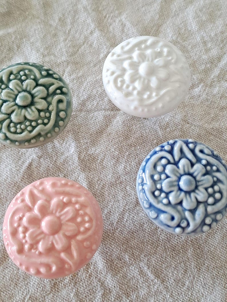 May include: Four ceramic knobs with a floral design. The knobs are in shades of white, blue, green, and pink.