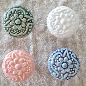 May include: Four ceramic knobs with a floral design. The knobs are in shades of green, white, pink, and blue.