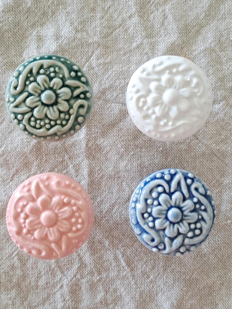 May include: Four ceramic knobs with a floral design. The knobs are in shades of green, white, pink, and blue.