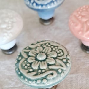 May include: Four ceramic drawer knobs with floral designs. The knobs are in shades of blue, white, pink, and green.