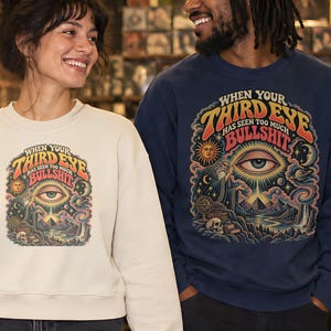 May include: Three long-sleeve crewneck sweatshirts in maroon, cream, and navy blue. Each features a colorful graphic print with the text "WHEN YOUR THIRD EYE HAS SEEN TOO MUCH BULLSHIT" above an illustration of an eye, sun, moon, and landscape.