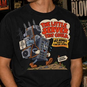 Op de afbeelding: Een zwart t-shirt met een afbeelding van een cartoon servereenheid die elektrische apparatuur op zijn rug draagt. De tekst luidt: The Little Server That Could. 65 Homes Worth Of Can-Do Spirit. Een bord wijst naar A Brighter Tomorrow.