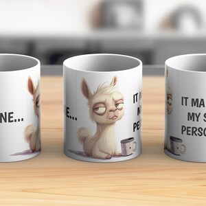 Könnte beinhalten: Weiße Keramiktasse mit einer Cartoon-Lama-Illustration und dem Text "It maintains my sunny personality". Das Lama hält eine kleine Kaffeetasse.