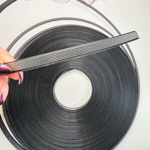 以下が含まれることがあります： 表面がテクスチャ加工された黒い面ファスナーのロール。テープは巻かれており、さまざまなプロジェクトに使用できます。