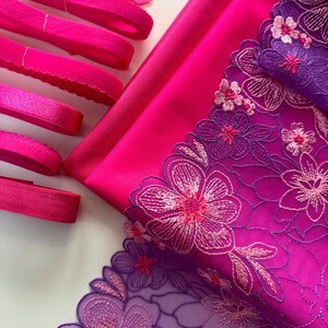 Op de afbeelding: Roze en paarse bloemenkant met roze elastisch lint en stof.