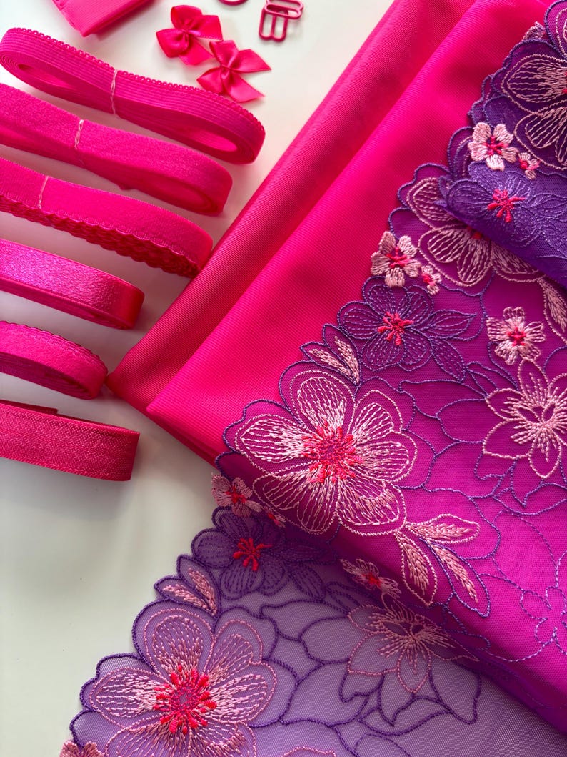Op de afbeelding: Roze en paarse bloemenkant met roze elastisch lint en stof.