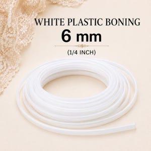 May include: A coil of white plastic boning with text that reads WHITE PLASTIC BONING 6 mm (1/4 INCH). The flexible, smooth material is arranged in a circular spiral shape, providing a clear view of the width and structure of this sewing supply.