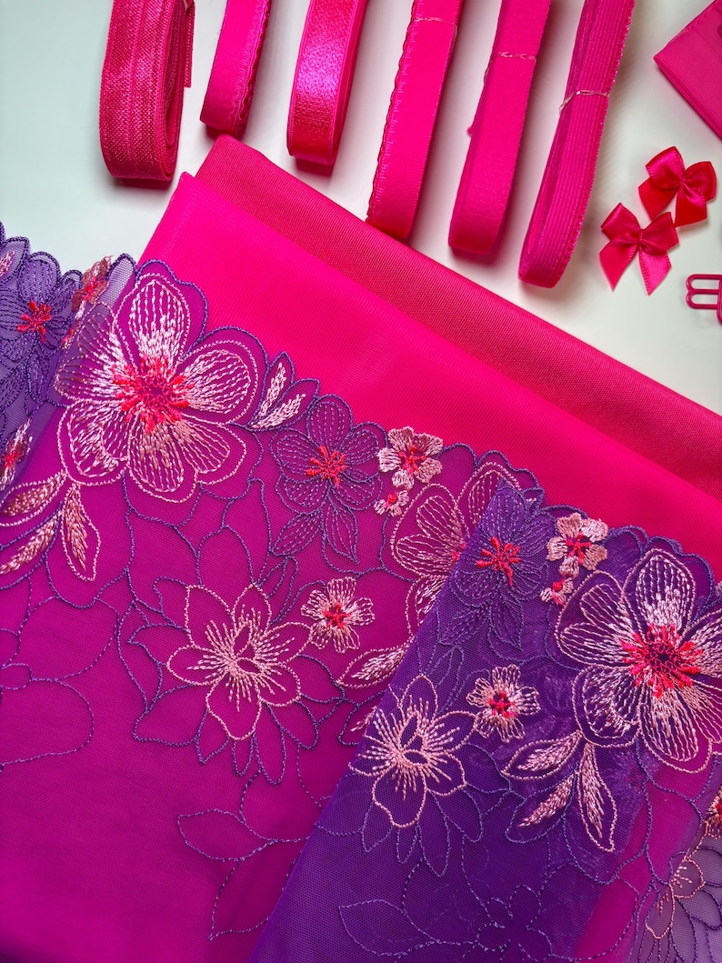 Op de afbeelding: Roze en paarse bloemenkant met roze satijnen lint en roze elastische trim. Deze stof is perfect voor knutsel- en naaiprojecten.