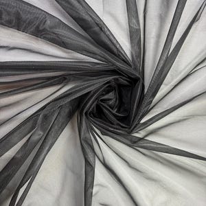 May include: Black sheer tulle fabric with a soft, delicate texture. The fabric is draped and gathered, creating a flowing and elegant look.