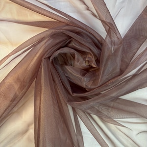 May include: A sheer brown fabric with a shimmery finish. The fabric is draped and folded, showing its texture and drape.