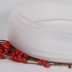 May include: A close-up of a white plastic cord, coiled in a circle. The cord is smooth and shiny, and it is likely used for crafts or other projects.