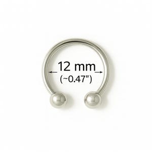 May include: A silver-colored horseshoe-shaped piercing ring with two small, round ball ends. The text indicates a diameter of 12 mm (~0.47 inches). The jewelry is set against a plain white background.