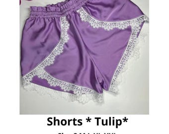May include: Purple satin shorts with white lace trim. The shorts have a tulip shape and are labeled "Shorts *Tulip*" and "Size S M L XL XXL Sewing Pattern".