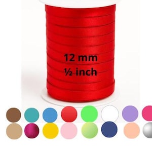 May include: A spool of bright red satin ribbon, 1/2 inch wide, with the text "12 mm" and "1/2 inch" printed on the side. A color palette of various colors is displayed below the spool.