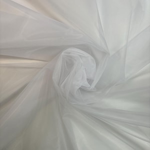 May include: White tulle fabric, a sheer and delicate material with a soft, flowing texture. It is often used for crafting, sewing, and decorating.