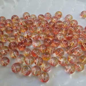 May include: A pile of translucent round beads with a red and yellow marbled pattern.