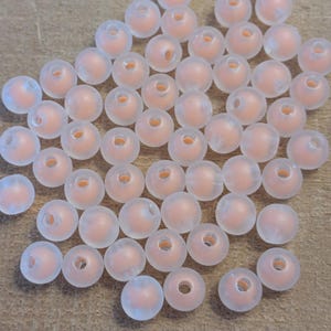 May include: A large group of translucent, peach-colored beads. The beads are round and have a smooth, frosted finish.