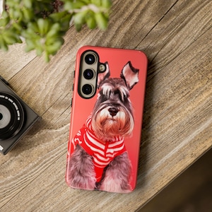 Könnte beinhalten: Eine rote Handyhülle mit schwarzem Rand und einem Foto eines grau-weißen Schnauzers, der einen rot-weiß gestreiften Pullover trägt.