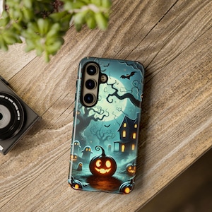 May include: A black phone case with a Halloween-themed design. The design features a spooky house, a full moon, a bat, and a jack-o'-lantern. The phone case has a cutout for the camera lens.