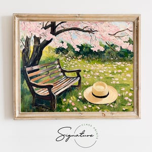 May include: A painting of a wooden bench under a blooming cherry tree with pink blossoms. A straw hat sits on the grass in front of the bench. The painting is framed in a light wood frame.