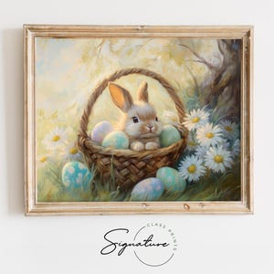 Puede incluir: Pintura enmarcada que representa un conejito esponjoso en una cesta tejida llena de huevos de Pascua pastel. El conejito está rodeado de margaritas blancas y exuberante vegetación, creando una escena primaveral serena. La pintura tiene un estilo suave y pictórico.