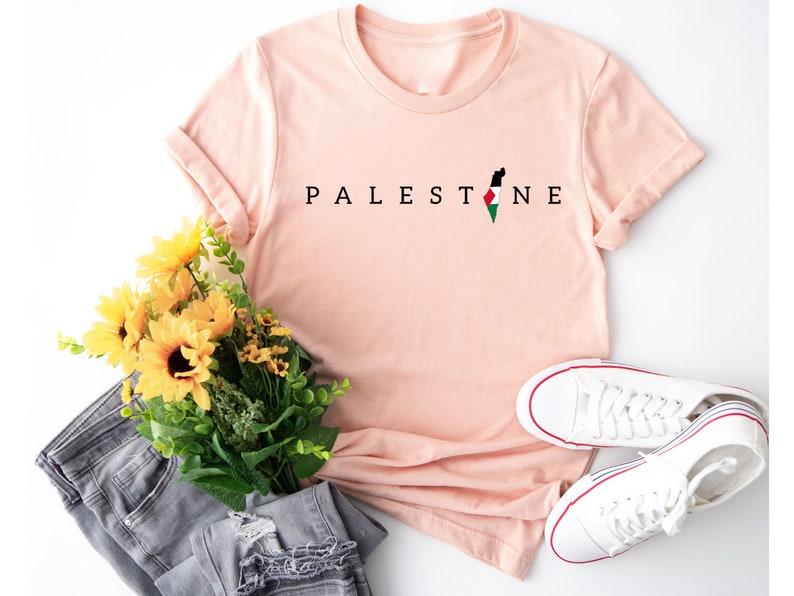 a pink shirt that says palestine next to a bouquet of flowers