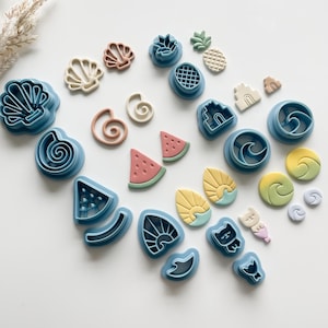 May include: A set of 20 blue, green, pink, and white plastic cookie cutters shaped like seashells, pineapples, watermelons, waves, suns, and other summer-themed designs.