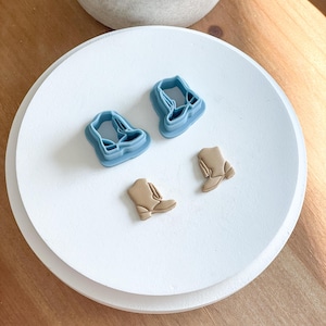 May include: Three cookie cutters in the shape of boots. Two are blue and one is brown.