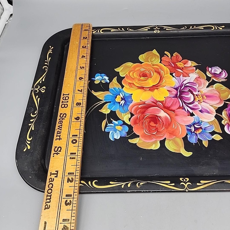 May include: Black rectangular serving tray with a floral design. The tray features a bouquet of colorful flowers in shades of orange, red, purple, and blue. The tray is approximately 14 inches long.