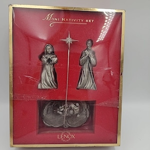 May include: Miniature nativity set in a red box with gold trim. The set includes silver-colored figurines of Mary, Joseph, and baby Jesus in a manger, along with a star. The box reads "Mini Nativity Set" and "LENOX".