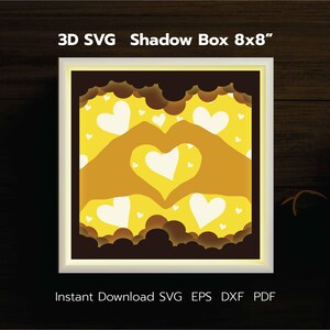 Könnte beinhalten: Ein 3D-Schattenkasten-Design mit zwei Händen, die eine Herzform mit gelbem Hintergrund und weißen Herzen bilden. Die Box ist 20,32 x 20,32 cm groß und steht zum sofortigen Download in den Formaten SVG, EPS, DXF und PDF zur Verfügung.