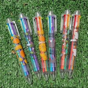 May include: Six multi-colored multi-pencils with colorful designs and the text "Guess What" on each. The designs include fruit, flowers, and a cartoon animal.