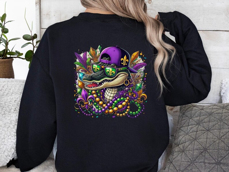 May include: Black sweatshirt with a purple and green alligator wearing a purple and gold Mardi Gras hat and sunglasses. The alligator is surrounded by Mardi Gras beads and other decorations.