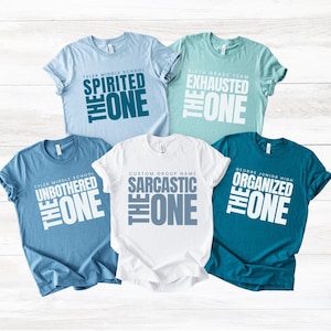 May include: Five short-sleeved t-shirts in various colors, including light blue, teal, and white. Each shirt features a different phrase in bold white and gray text, such as "SPIRITED THE ONE" and "SARCASTIC THE ONE".