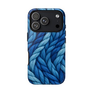 May include: A smartphone case featuring a blue knit pattern. The case has a glossy finish and a camera cutout with three lenses. The design incorporates varying shades of blue, creating a textured appearance. The case is designed to fit a smartphone.