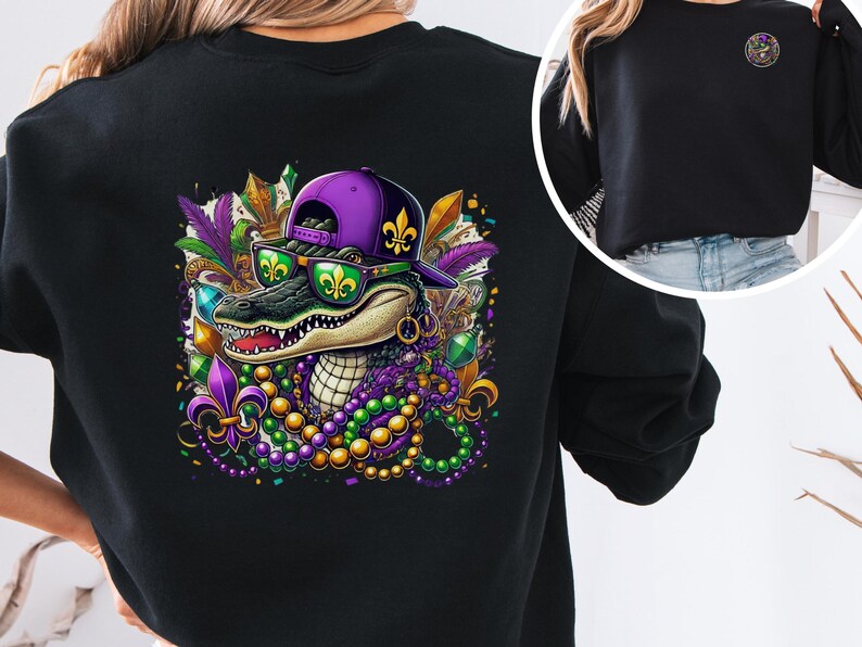 May include: Black sweatshirt with a colorful graphic of an alligator wearing a purple hat and sunglasses, surrounded by Mardi Gras beads and other decorations.