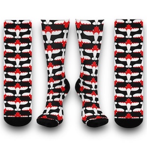 May include: A pair of black and white socks with a red airplane pattern. The socks are knee-high and have a black cuff.
