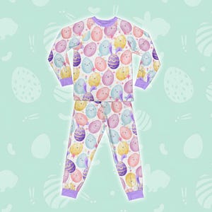May include: A white long-sleeved pyjama top and matching trousers with a colourful Easter egg pattern. The eggs are decorated with purple, pink, blue and yellow watercolour designs.