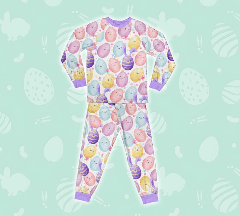 May include: A white long-sleeved pyjama top and matching trousers with a colourful Easter egg pattern. The eggs are decorated with purple, pink, blue and yellow watercolour designs.