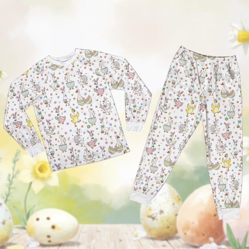 May include: White pajama set featuring a repeating pattern of geese, bunnies, and Easter eggs. The long-sleeved top and pants have a soft, comfortable appearance. The design includes pastel colors and floral accents, perfect for Easter or spring.