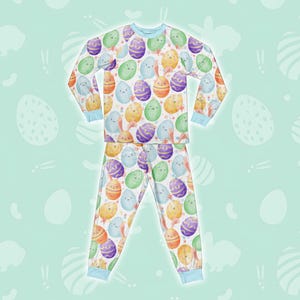 May include: A white long-sleeved pyjama top and matching trousers with a colourful Easter egg pattern. The eggs are decorated with different colours and have cute faces.