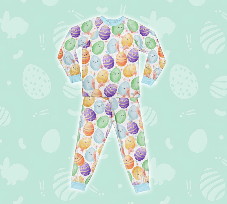 May include: A white long-sleeved pyjama top and matching trousers with a colourful Easter egg pattern. The eggs are decorated with different colours and have cute faces.
