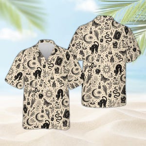 May include: A short-sleeve button-down shirt in a light beige color featuring an all-over black ink-style print. The pattern includes illustrations of cats, snakes, moths, crescent moons, suns, crystal balls, candles, and various botanical elements.