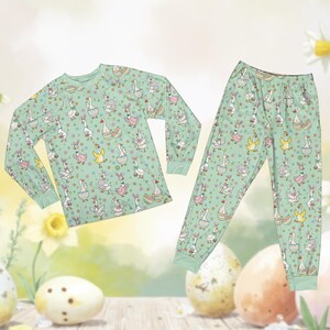 May include: A two-piece pajama set featuring a light green background with a repeating pattern of cartoon geese wearing Easter-themed accessories. The long-sleeved top and pants have matching cuffs and a whimsical design.