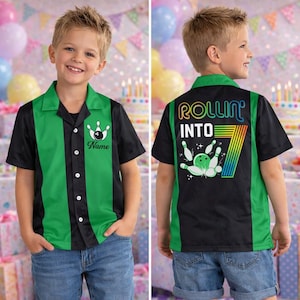 May include: A bowling-themed button-up shirt with a green and black color scheme. The front features a bowling pin graphic and the word "Name". The back of the shirt says "ROLLIN' INTO 7" with a bowling ball and pins graphic. The shirt is worn with blue denim shorts.