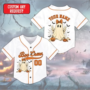 May include: A white baseball jersey with orange trim featuring a ghost graphic, pumpkins, bats, and spiderwebs. The front displays the text "Boo Crew" and the number "00". The back features the text "YOUR NAME" above a ghost graphic.