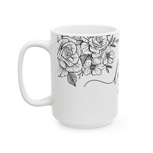 K&ouml;nnte beinhalten: Wei&szlig;e Keramiktasse mit schwarzem Blumendesign und dem Text "Love you more" an der Seite.