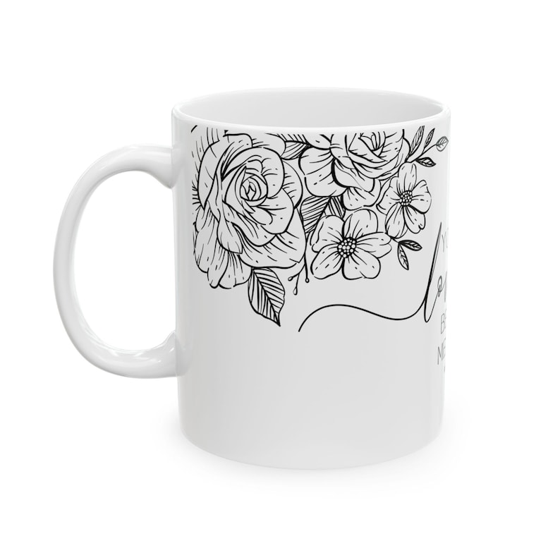 K&ouml;nnte beinhalten: Wei&szlig;e Keramiktasse mit schwarzem Blumendesign und dem Text "Let your light shine" an der Seite.