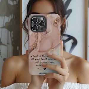 May include: A pink and gold marble phone case with a quote from Proverbs 3:5: "Trust in the Lord with all your heart and lean not on your own understanding."