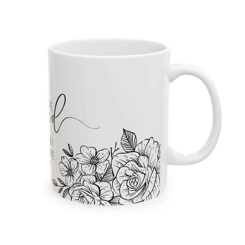 K&ouml;nnte beinhalten: Wei&szlig;e Keramiktasse mit schwarzem Blumendesign und dem Text "Sei nett zu dir selbst" in kursiv.